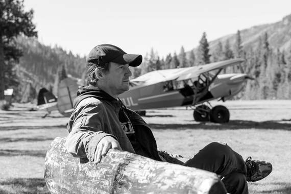 A pilot resting on a log beside his Cub